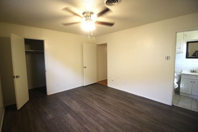 unfurnished bedroom with sink, a textured ceiling, and dark hardwood / wood-style floors