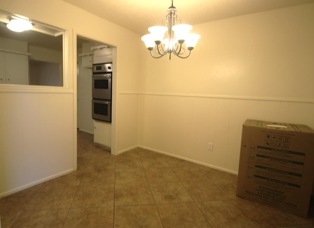 spare room featuring a notable chandelier and dark tile patterned floors