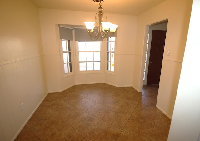 tiled empty room featuring an inviting chandelier