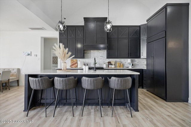 9105 Kewanee Ave, Lubbock, TX 79424 - kitchen with tasteful backsplash, light countertops, a sink, light wood finished floors, and an island with sink