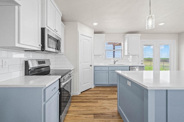 kitchen featuring white cabinetry, stainless steel appliances, decorative light fixtures, and sink