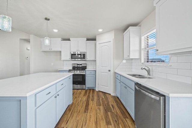 kitchen with dark wood-type flooring, sink, decorative light fixtures, appliances with stainless steel finishes, and white cabinets