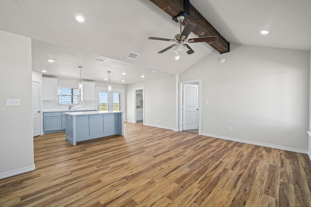 kitchen with white cabinetry, hanging light fixtures, light hardwood / wood-style flooring, a kitchen island, and backsplash