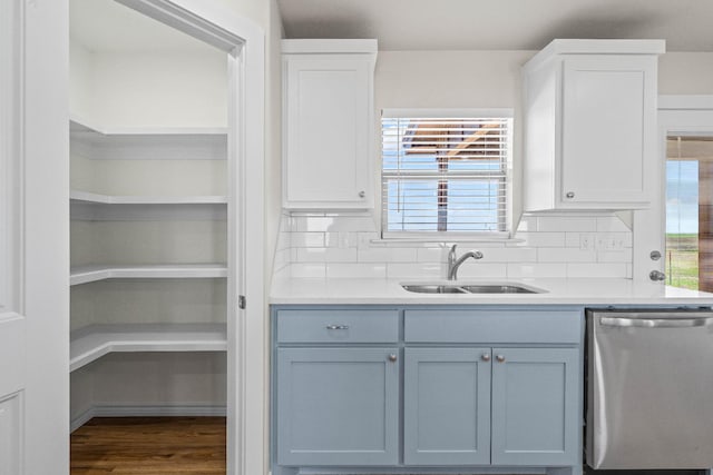 kitchen featuring white cabinetry, stainless steel dishwasher, sink, and hardwood / wood-style floors