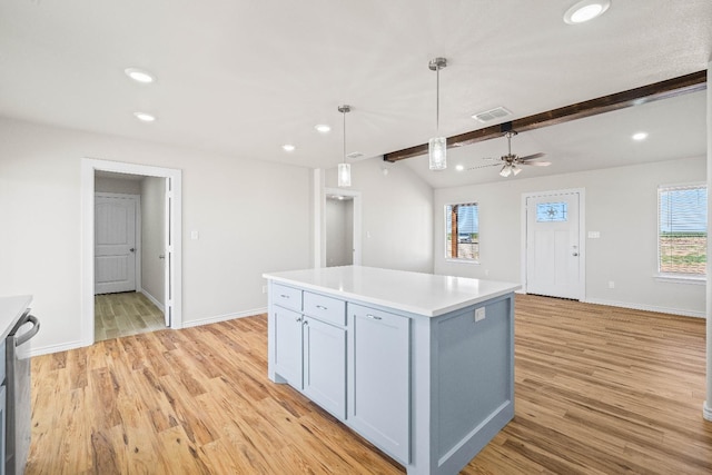 kitchen with decorative light fixtures, vaulted ceiling with beams, a center island, ceiling fan, and light hardwood / wood-style flooring