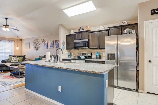 kitchen featuring sink, appliances with stainless steel finishes, backsplash, dark brown cabinetry, and a center island with sink