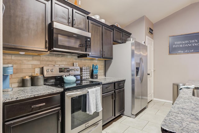 kitchen with vaulted ceiling, dark brown cabinets, light tile patterned floors, stainless steel appliances, and decorative backsplash