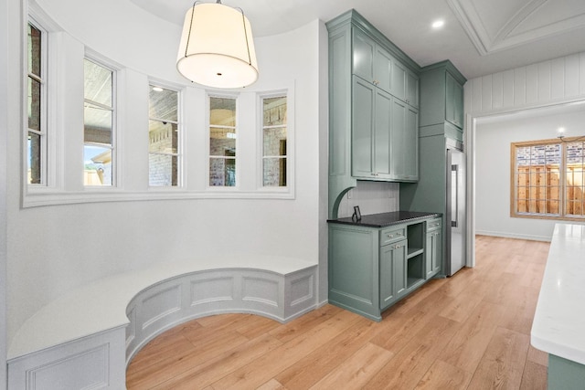 interior space featuring green cabinetry, high end refrigerator, decorative light fixtures, dark stone countertops, and light wood-type flooring