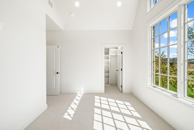 interior space with a high ceiling, a walk in closet, light carpet, and a closet