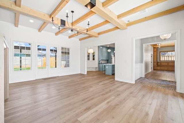 unfurnished living room with an inviting chandelier, light wood-type flooring, french doors, and beamed ceiling