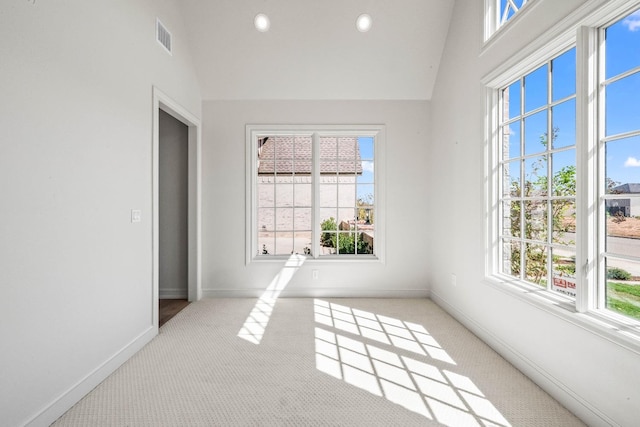 carpeted spare room with high vaulted ceiling and a healthy amount of sunlight