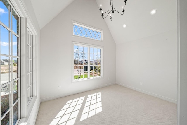 carpeted spare room with a notable chandelier and high vaulted ceiling