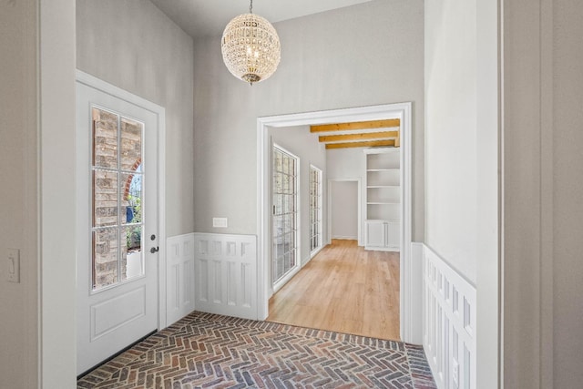 entryway with a notable chandelier and beam ceiling