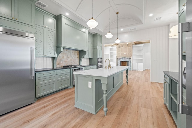 kitchen featuring stainless steel appliances, green cabinets, light hardwood / wood-style floors, and decorative light fixtures