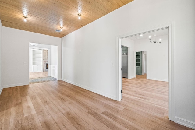 unfurnished room with an inviting chandelier, built in shelves, light hardwood / wood-style floors, and wooden ceiling