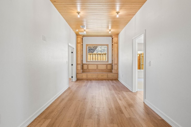 corridor featuring light hardwood / wood-style flooring and wooden ceiling