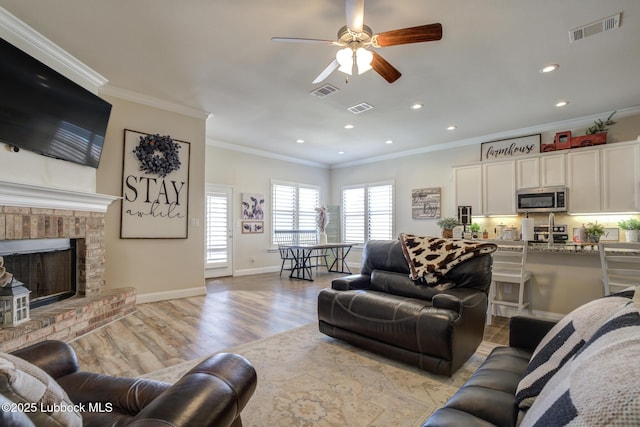 7204 90th St, Lubbock, TX 79424 - living room featuring crown molding, light wood finished floors, ceiling fan, recessed lighting, and a fireplace