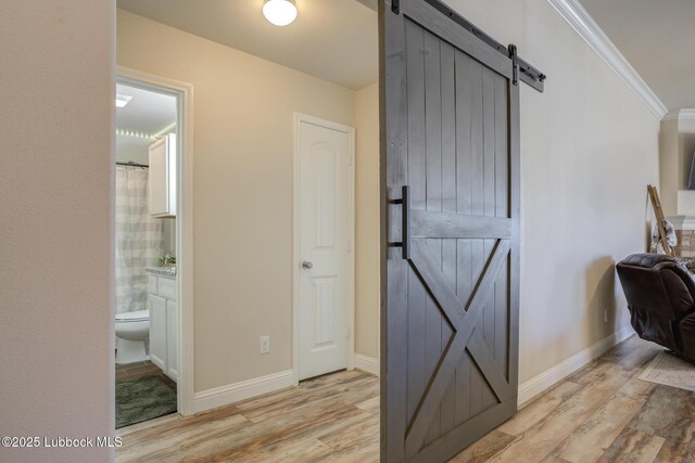7204 90th St, Lubbock, TX 79424 - corridor with a barn door, light wood finished floors, ornamental molding, and baseboards