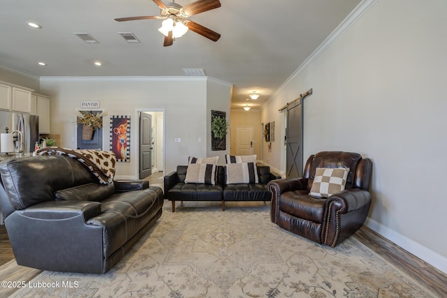 7204 90th St, Lubbock, TX 79424 - living area featuring a barn door, crown molding, light wood finished floors, a ceiling fan, and baseboards