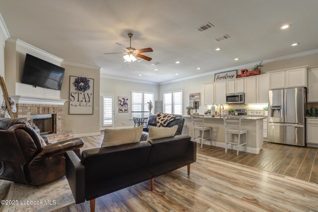 7204 90th St, Lubbock, TX 79424 - living room with a ceiling fan, crown molding, wood finished floors, a fireplace, and recessed lighting