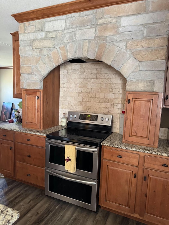 kitchen with range with two ovens, dark hardwood / wood-style flooring, and light stone counters