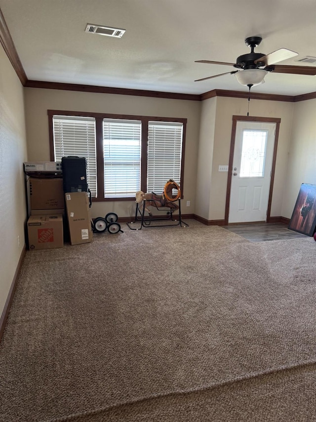 entryway featuring ornamental molding, ceiling fan, and carpet flooring