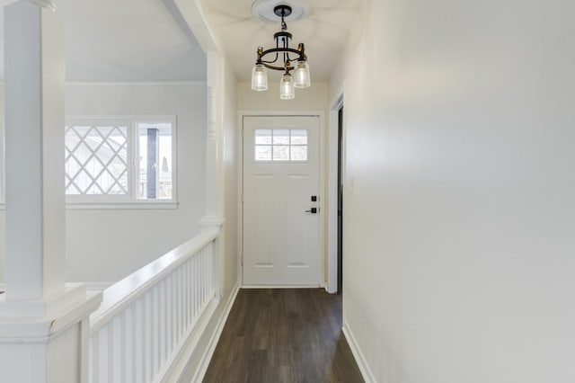 doorway to outside with an inviting chandelier, ornamental molding, dark hardwood / wood-style flooring, and ornate columns