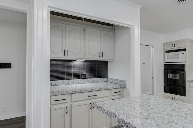 kitchen featuring white cabinets, white microwave, and oven