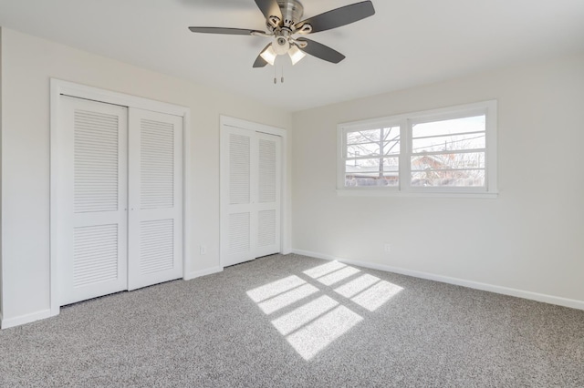 unfurnished bedroom with carpet, two closets, and ceiling fan