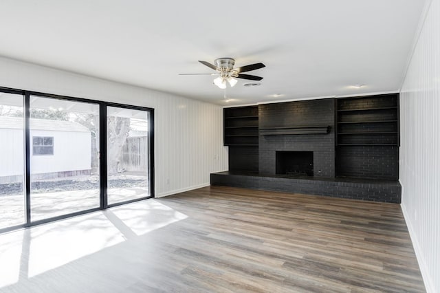 unfurnished living room featuring wood-type flooring, ceiling fan, and a fireplace