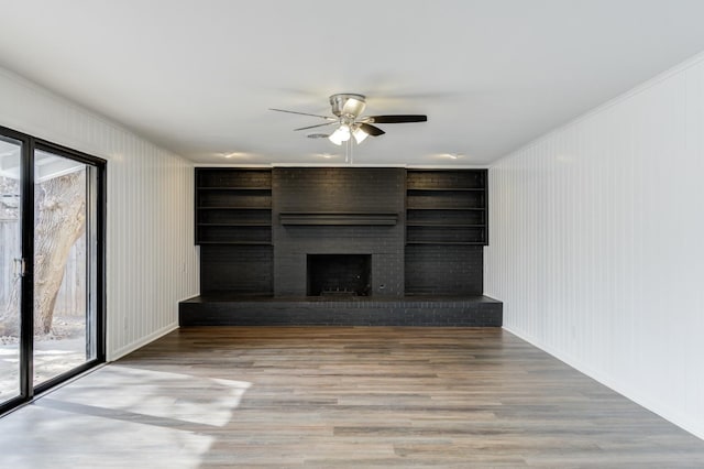 unfurnished living room featuring a brick fireplace, a wealth of natural light, wood-type flooring, and ceiling fan