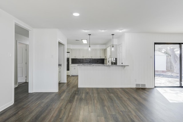 kitchen featuring dark wood-type flooring, white cabinetry, hanging light fixtures, kitchen peninsula, and light stone countertops