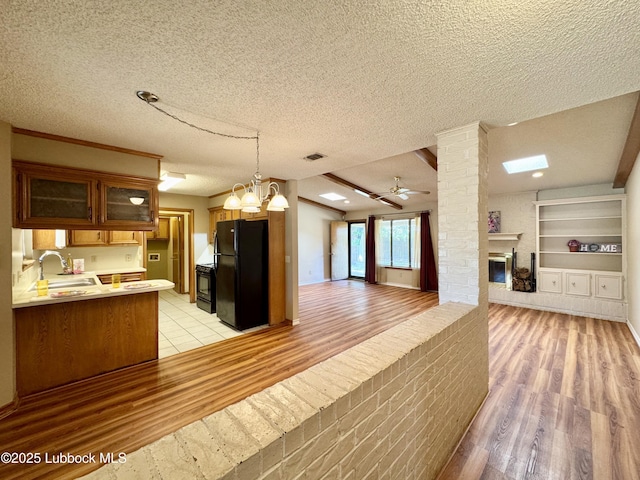5508 94th St, Lubbock, TX 79424 - kitchen with black appliances, open floor plan, light wood-style floors, a sink, and a textured ceiling