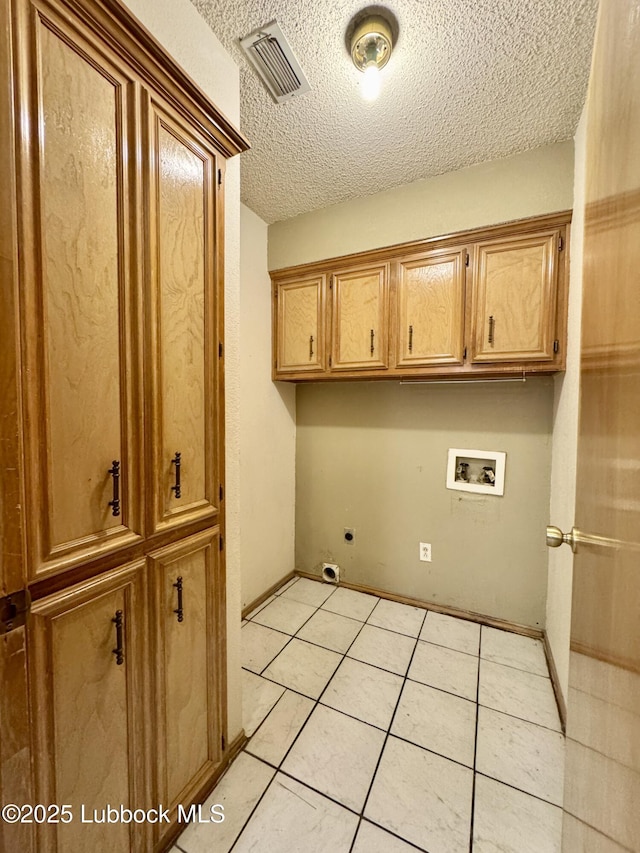 5508 94th St, Lubbock, TX 79424 - laundry room featuring cabinet space, hookup for a washing machine, a textured ceiling, hookup for an electric dryer, and light tile patterned flooring