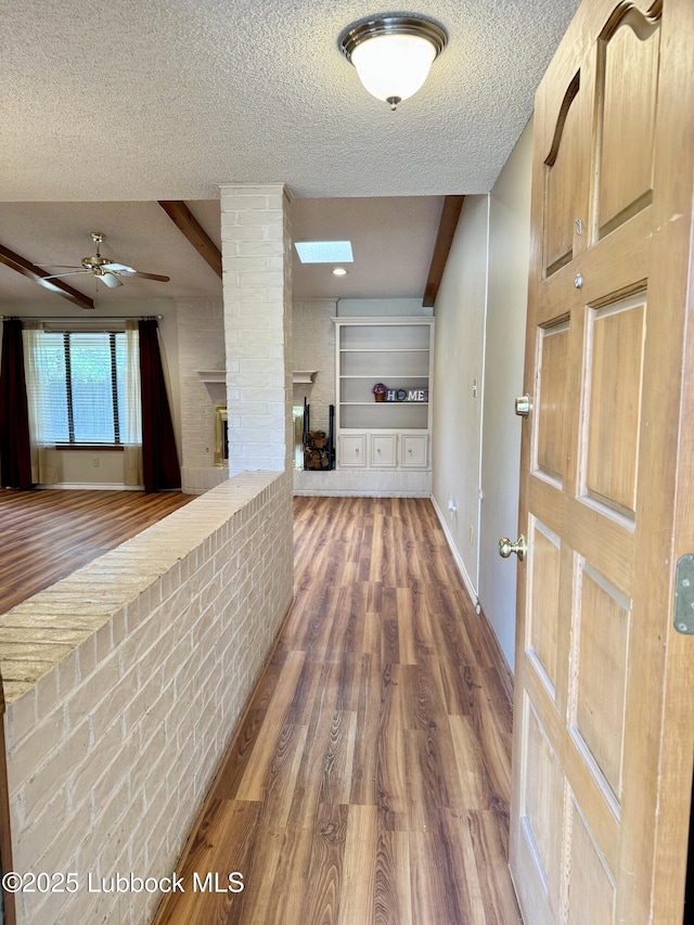 5508 94th St, Lubbock, TX 79424 - hall featuring a textured ceiling, wood finished floors, baseboards, and decorative columns