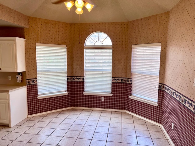 unfurnished dining area featuring lofted ceiling, light tile patterned floors, and ceiling fan