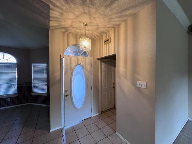 entrance foyer with light tile patterned floors, a textured ceiling, and a chandelier