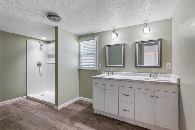 bathroom featuring hardwood / wood-style flooring, tiled shower, vanity, and a textured ceiling