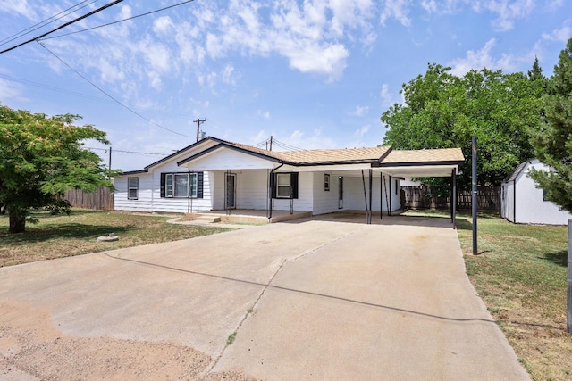 ranch-style house featuring a front lawn, a carport, and a storage unit