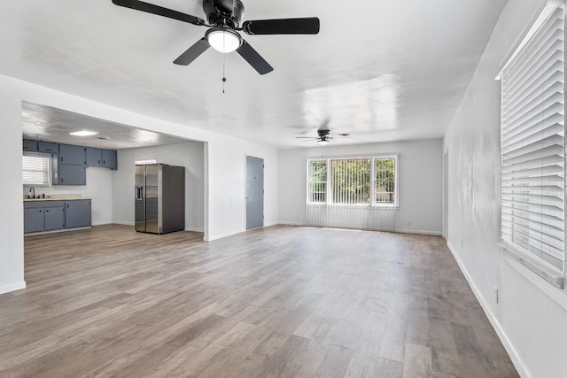 unfurnished living room featuring sink, light hardwood / wood-style flooring, and ceiling fan