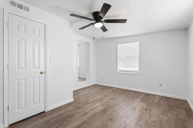 empty room with hardwood / wood-style flooring, ceiling fan, and a textured ceiling