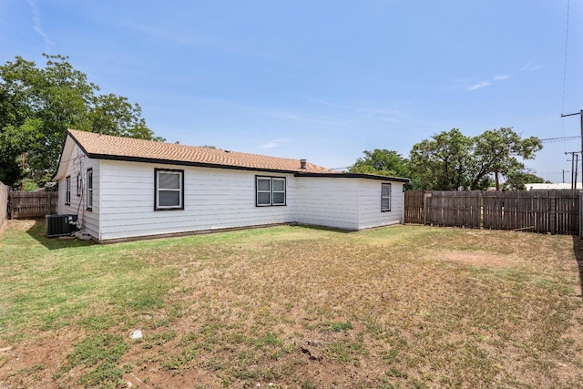 back of property with central AC unit and a lawn