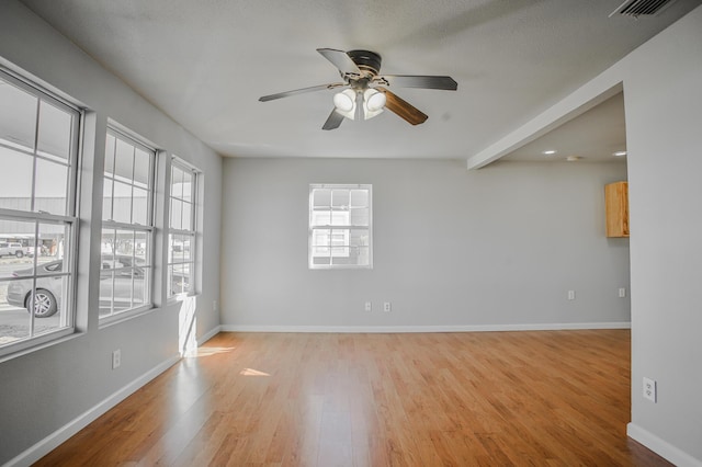 empty room featuring ceiling fan, beam ceiling, and light hardwood / wood-style flooring