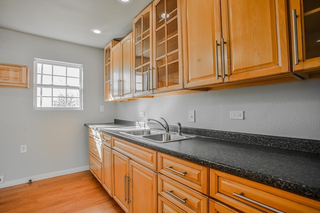 kitchen with light hardwood / wood-style floors, sink, and dark stone countertops