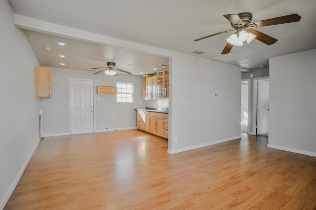 unfurnished living room featuring sink, ceiling fan, and light wood-type flooring