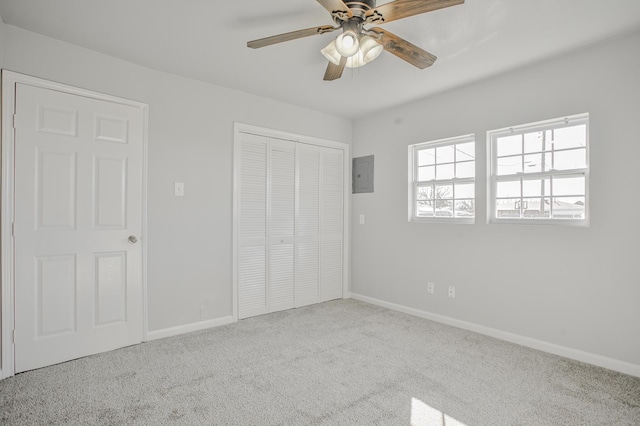 unfurnished bedroom featuring light carpet, electric panel, a closet, and ceiling fan