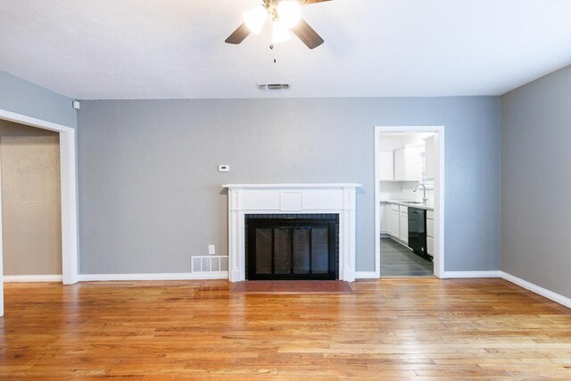 unfurnished living room with ceiling fan, sink, and light hardwood / wood-style floors