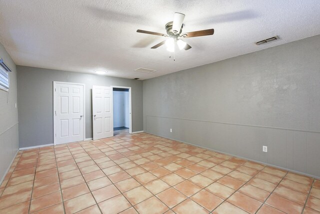 spare room with ceiling fan, light tile patterned floors, and a textured ceiling