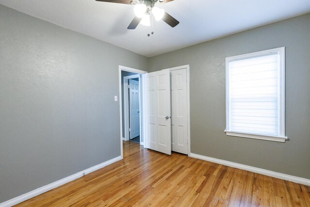 unfurnished bedroom with multiple windows, ceiling fan, and light wood-type flooring