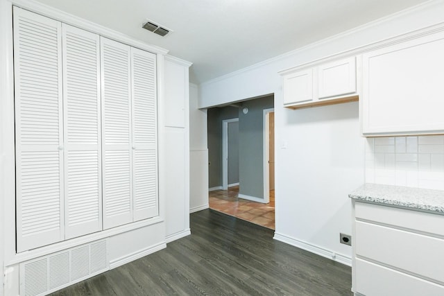 kitchen with backsplash, light stone counters, ornamental molding, white cabinets, and dark hardwood / wood-style flooring